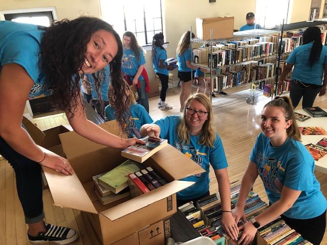 Day of Caring volunteers placing books into boxes